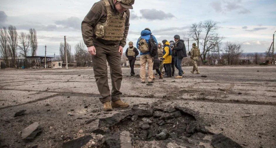 Ukrainian soldier looking at a hole from a shell fired by pro-Russian separatists in Luhansk region